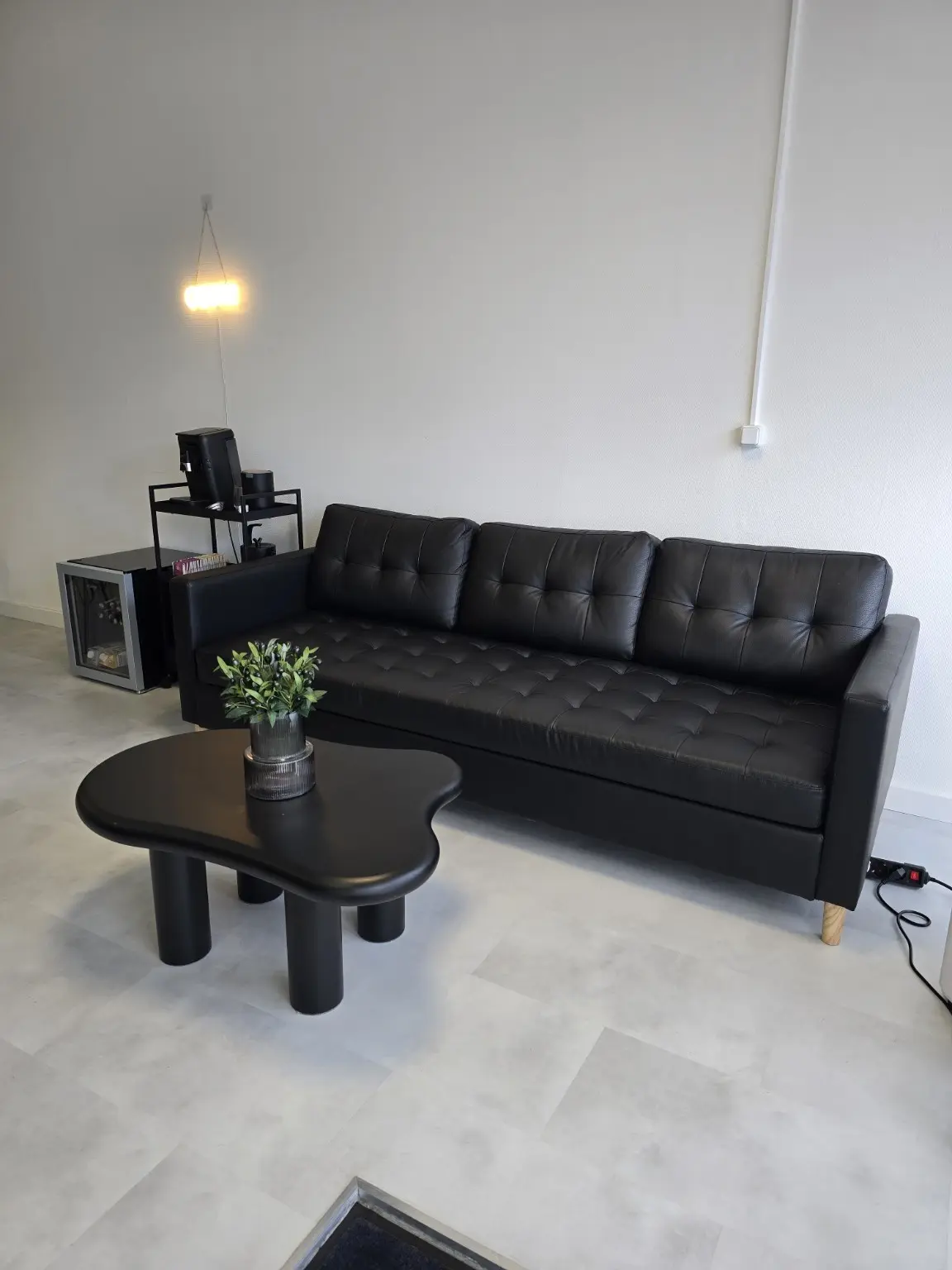 Schwarzes Sofa und Tisch im Wartebereich des Studios