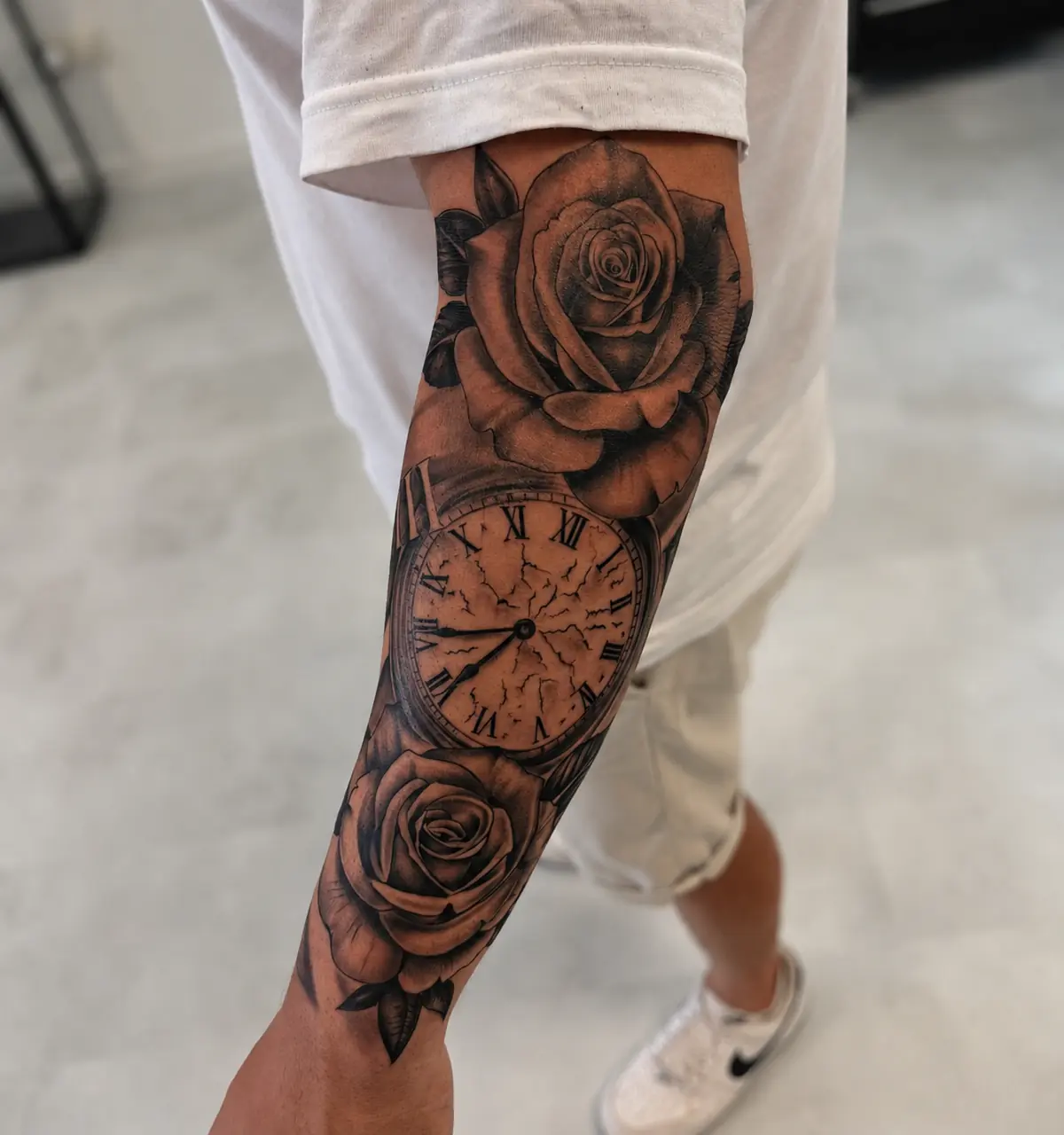Rosen und römische Uhr als Unterarmtattoo